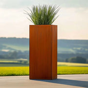 Tall rectangular metal planter with green grass against a scenic background